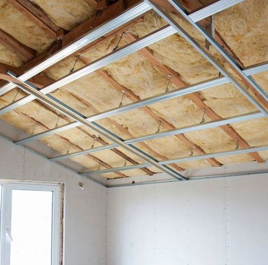 Interior view of a ceiling under construction with insulation, metal framing, and a partially built drywall.