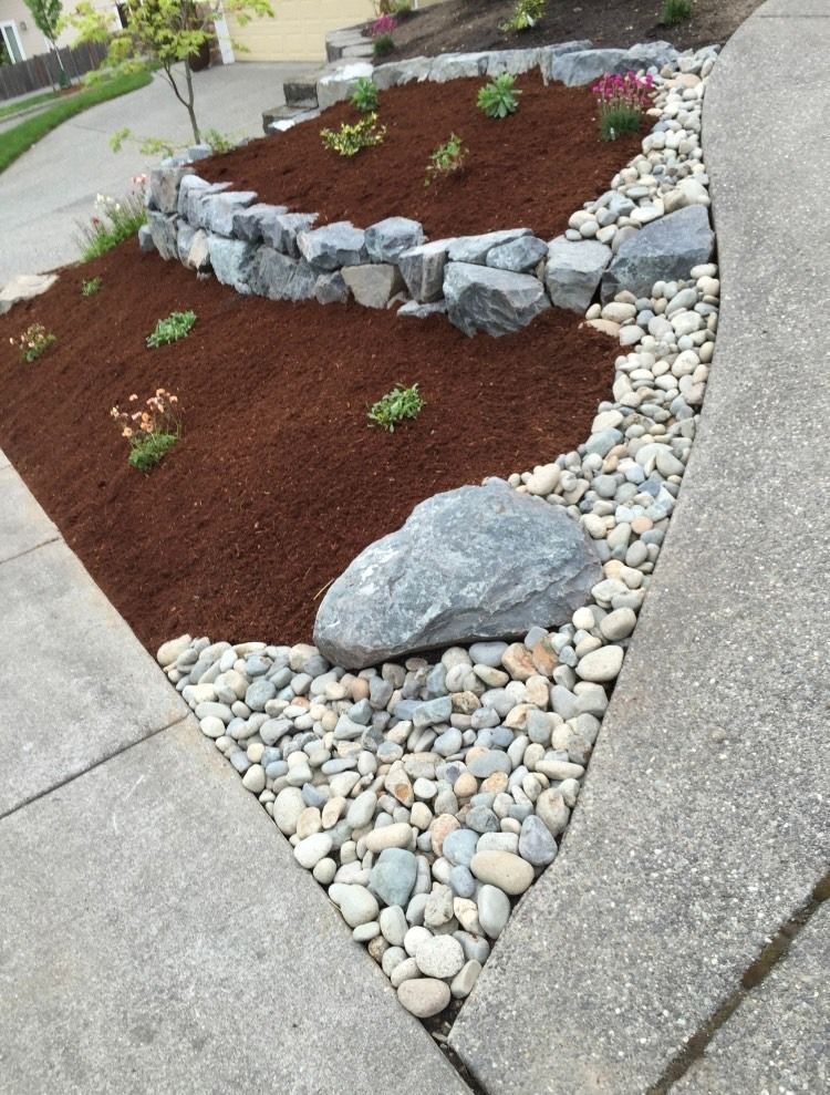 A corner of a garden with rocks and mulch in Monroe, WA.