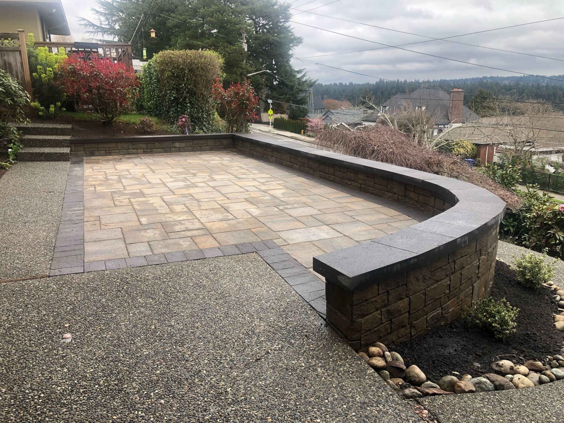 A brick patio with a stone wall and steps leading up to it in Monroe, WA.
