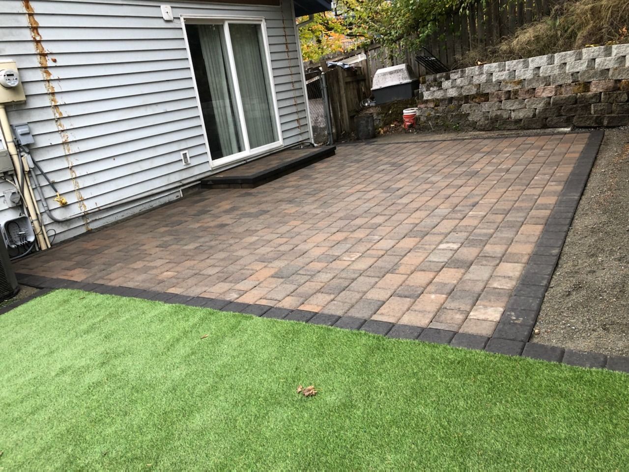 A patio with a sliding glass door and artificial grass in front of a house in Monroe, WA.