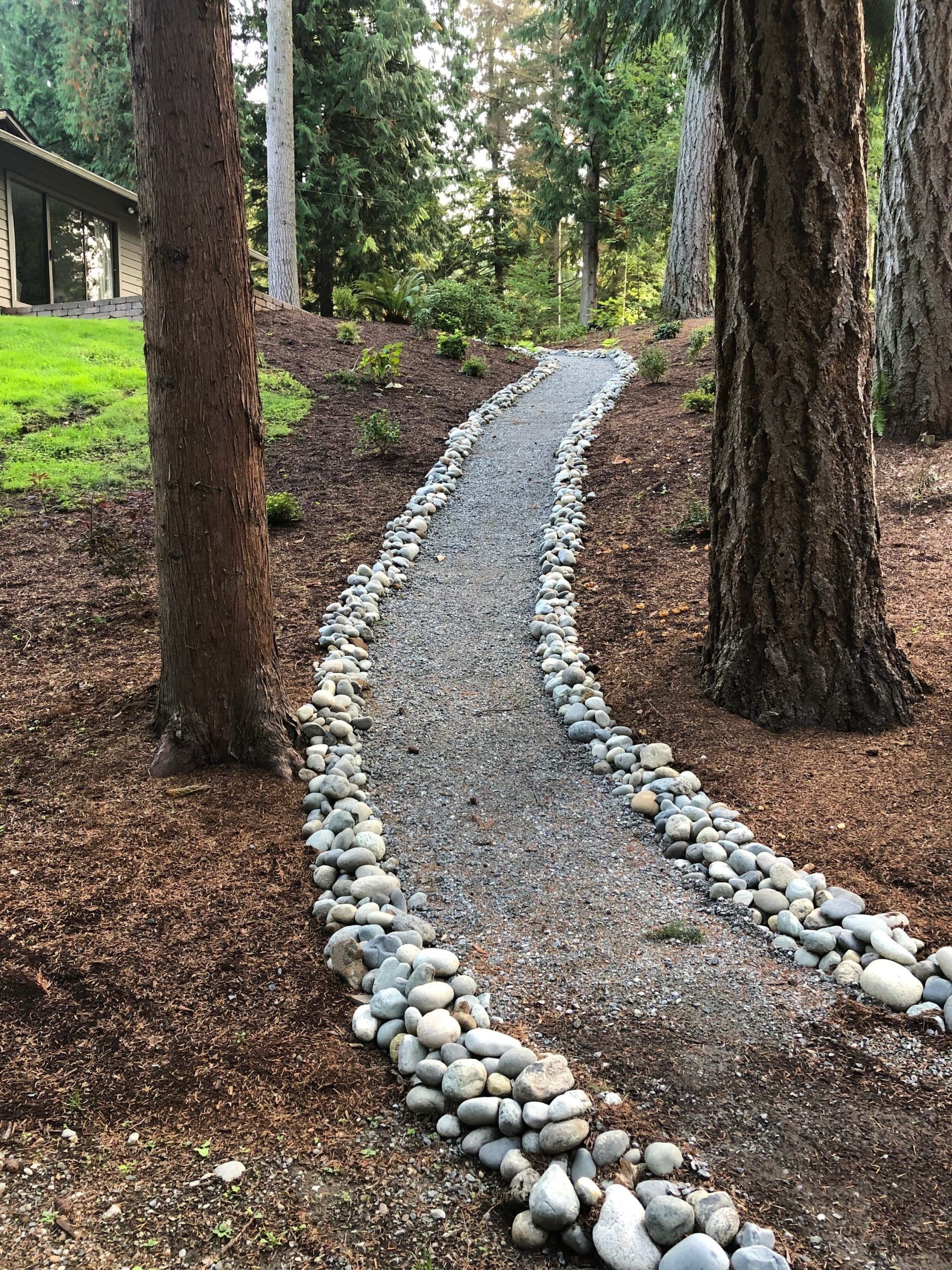 A gravel path surrounded by trees and rocks leading to a house in Monroe, WA.