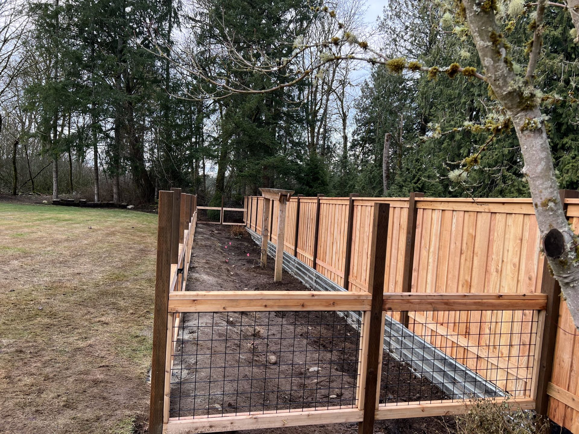 A wooden fence is being built in a field with trees in the background in Monroe, WA.