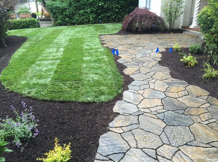 A stone walkway leading to a lush green lawn.