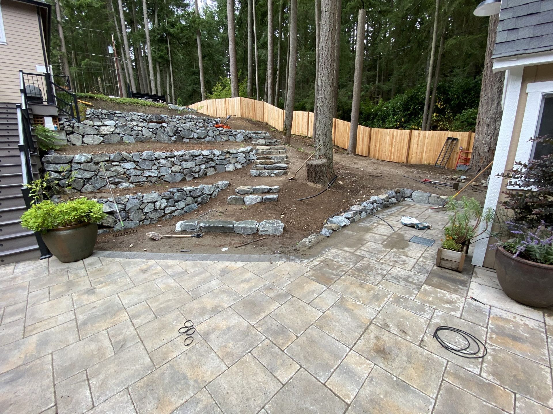 A stone wall is being built in the backyard of a house in Monroe, WA.