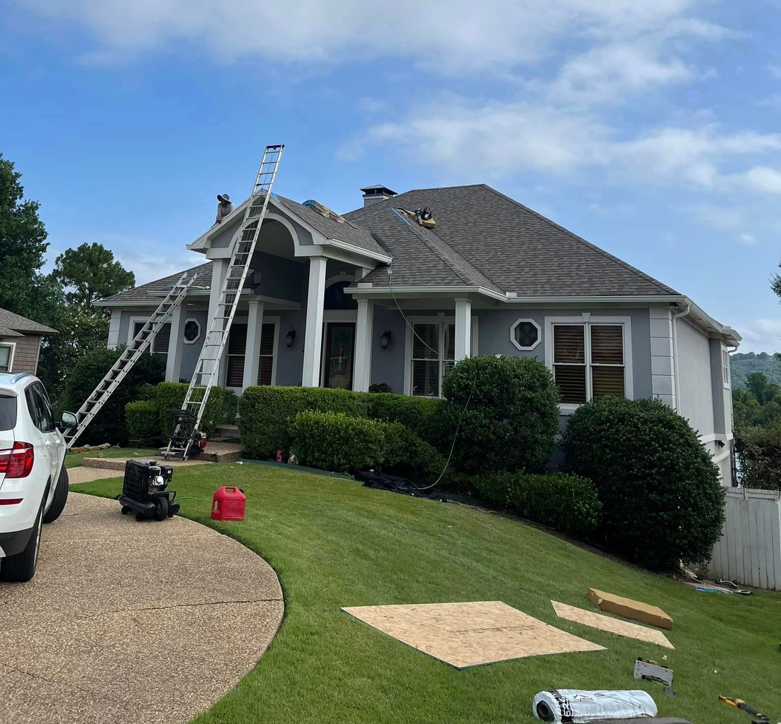A white truck is parked in front of a house that is being painted.