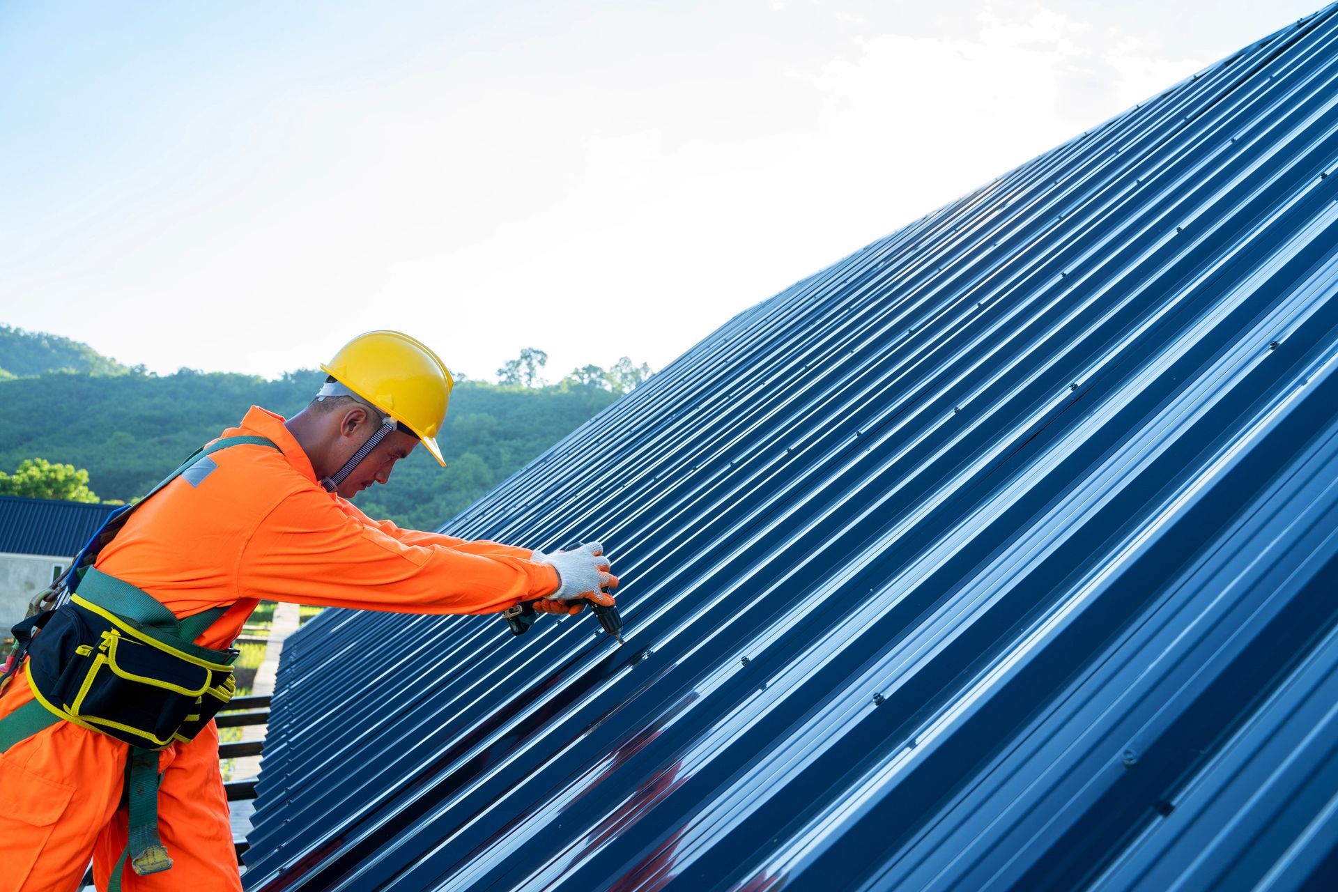 A man is working on a blue metal roof.