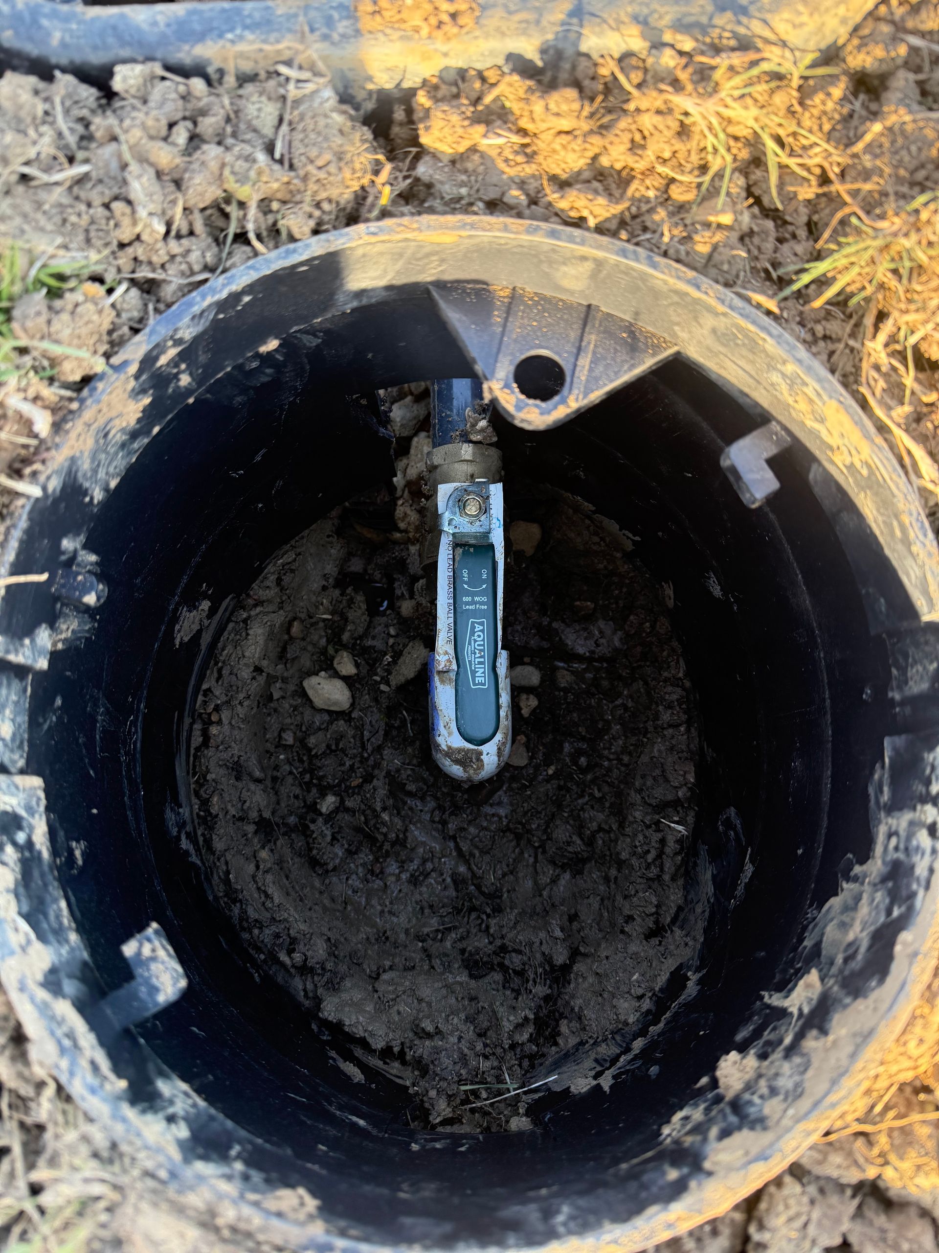 Open black valve box with a moisture sensor and dirt.