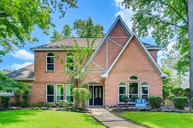Two-story red brick house with arched windows and a steep gabled roofline.