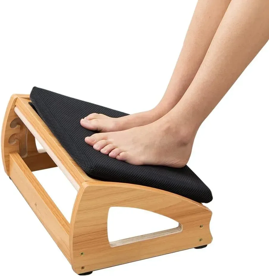 Feet on a black-cushioned wooden slant board for calf stretching or foot exercise