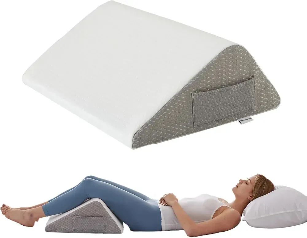 White wedge pillow shown with a person resting legs on it and head on a pillow, supporting a reclined position