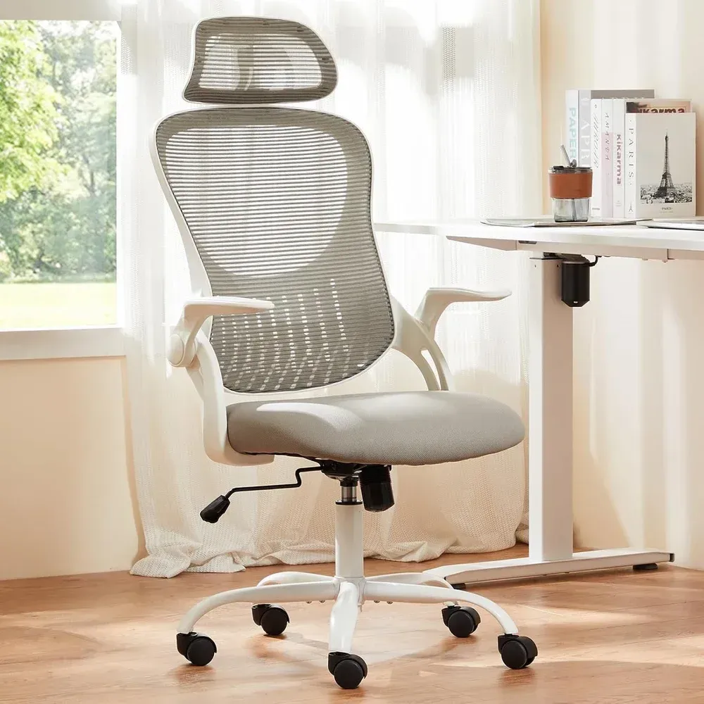 Gray mesh office chair by a desk in a bright room with a window and curtains