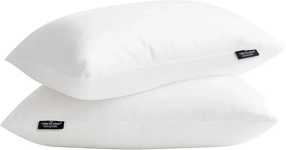 Two white pillows stacked on a white background with small black labels