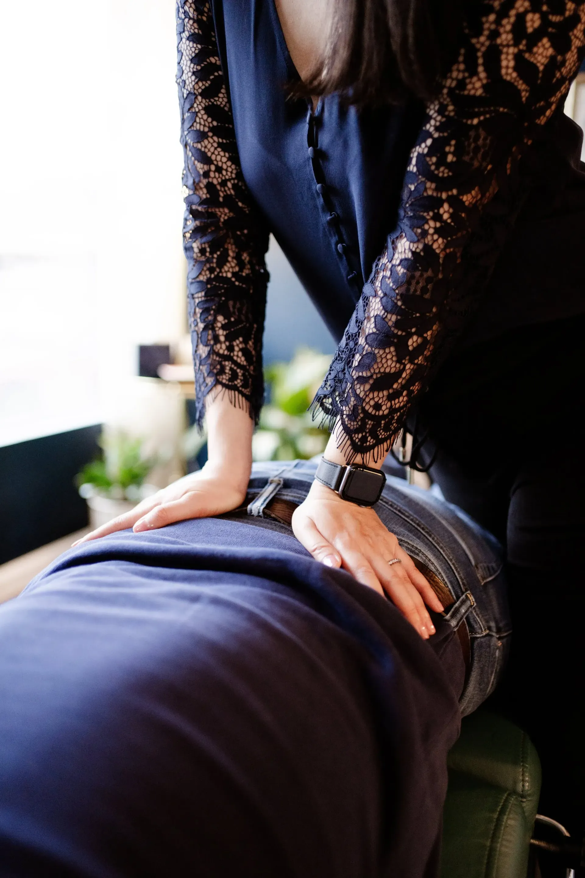 Person giving a back massage with hands on a client’s lower back in a bright room