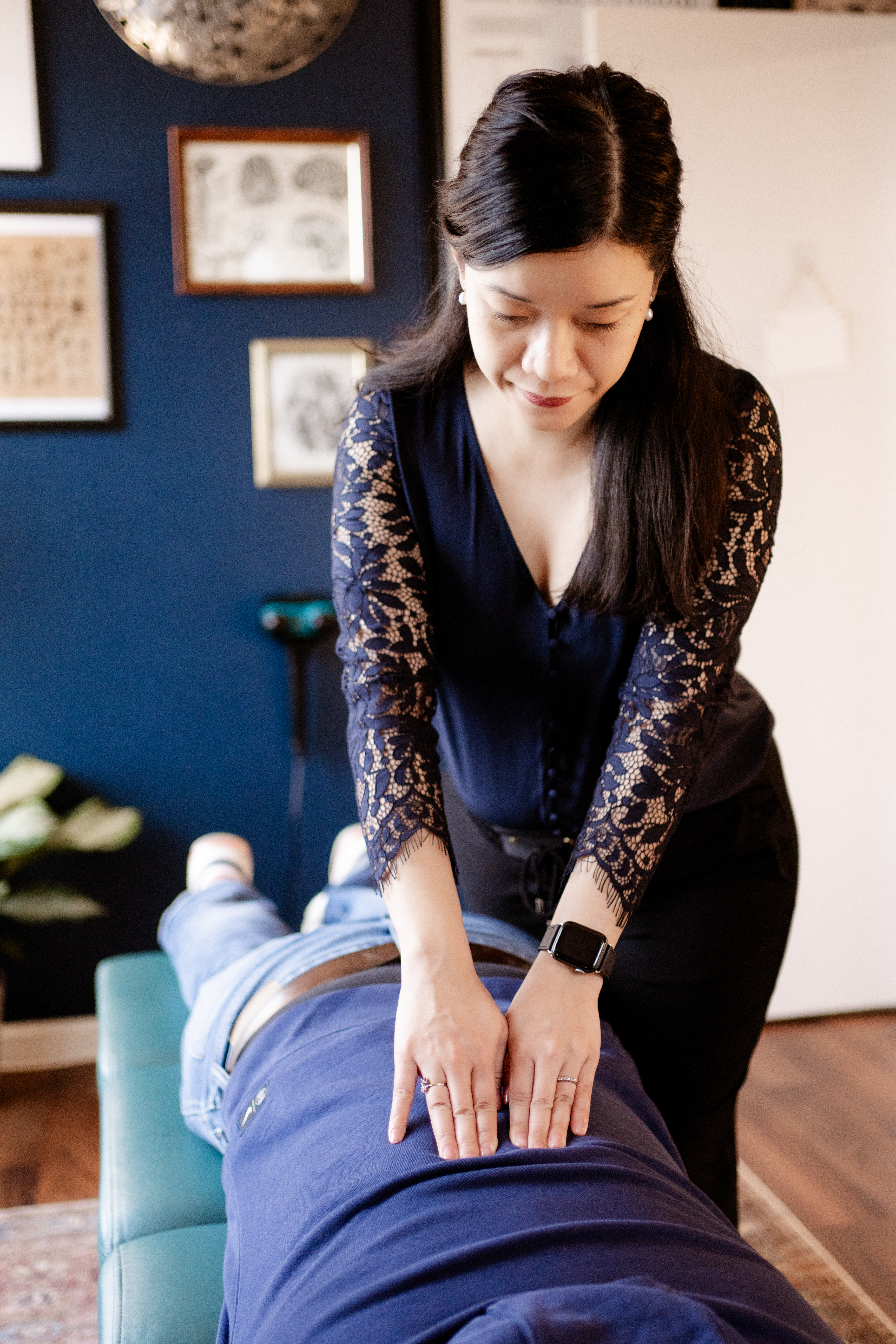 Massage therapist pressing on a client's back in a cozy room with framed wall art
