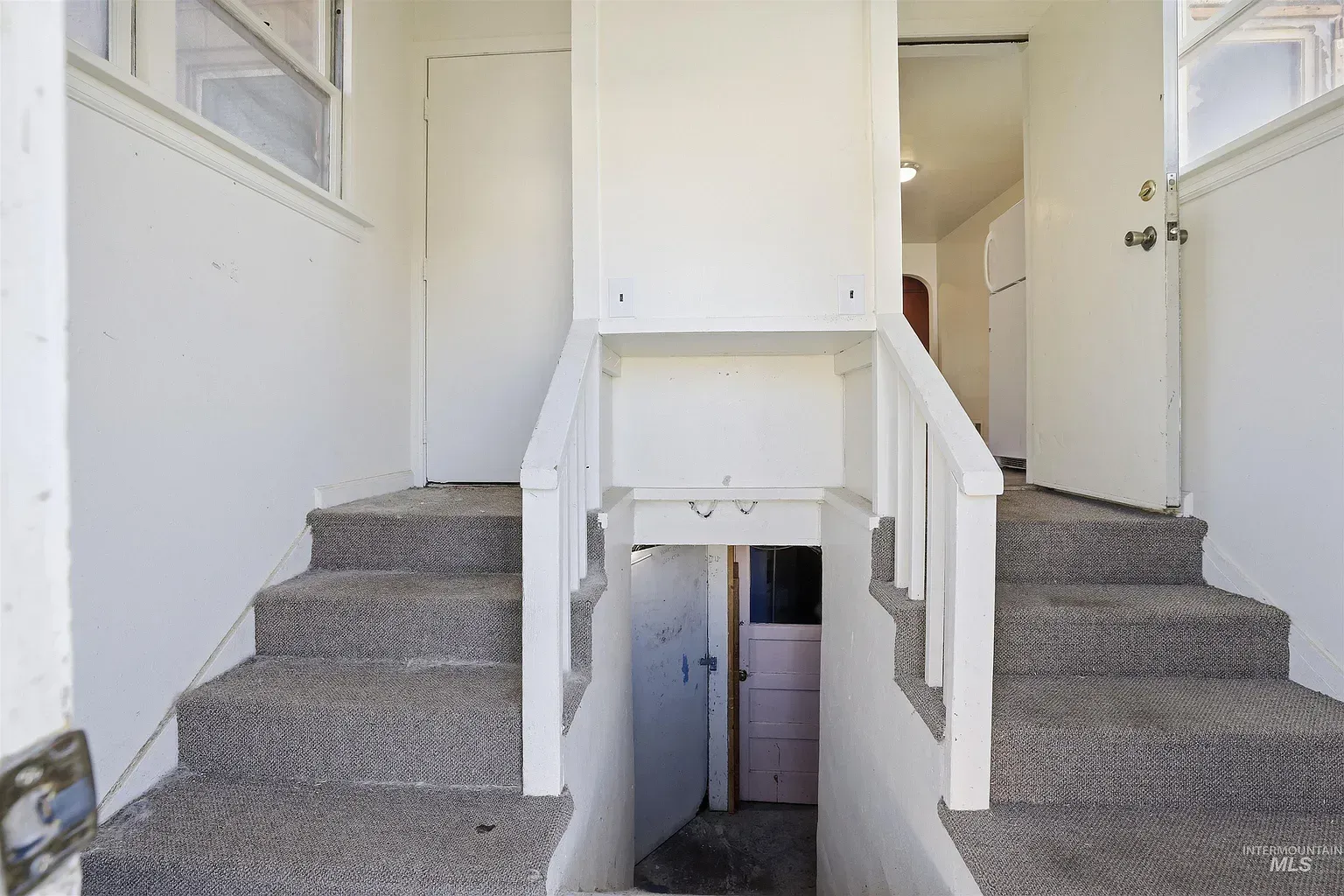 Interior staircase with carpeted steps split around a central open stairwell and white railings.