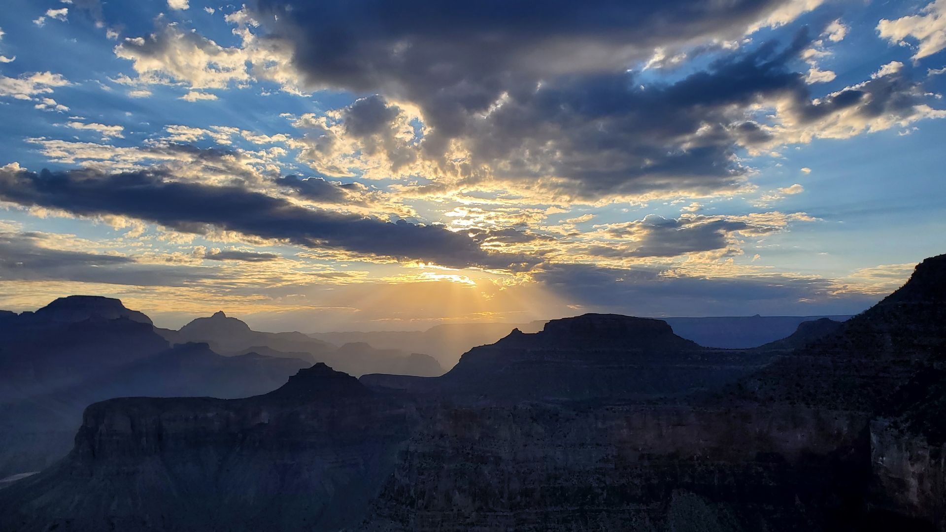 The sun is shining through the clouds over the grand canyon