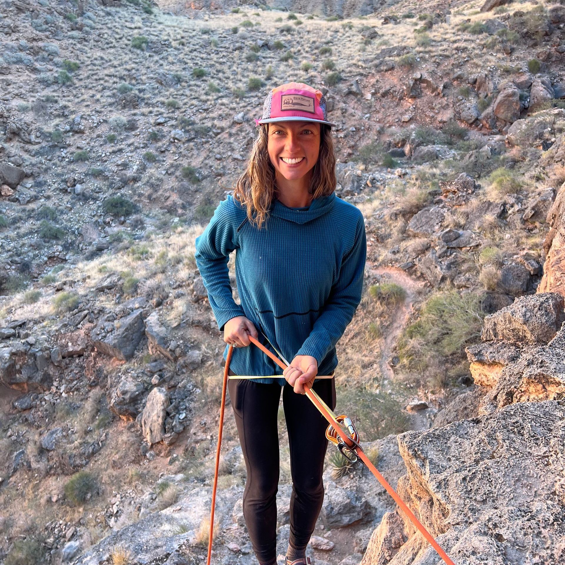 A woman wearing a hat is rappelling in Grand Canyon.