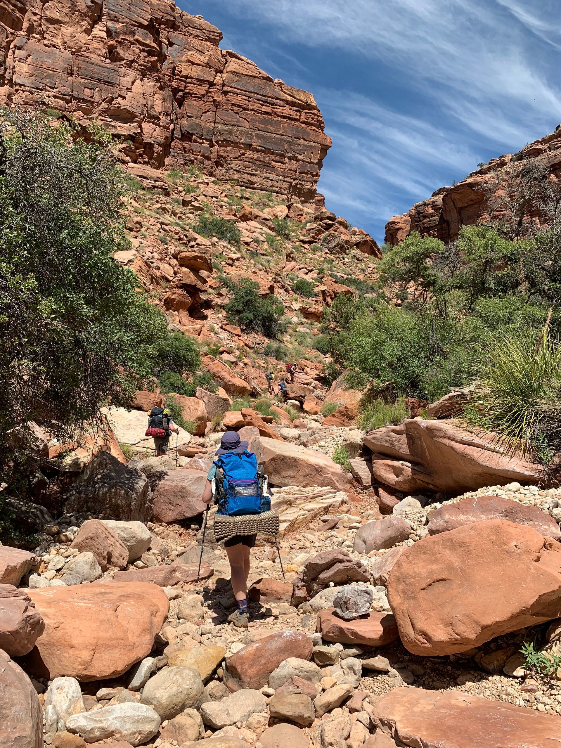 A person with a backpack is walking through a rocky canyon.
