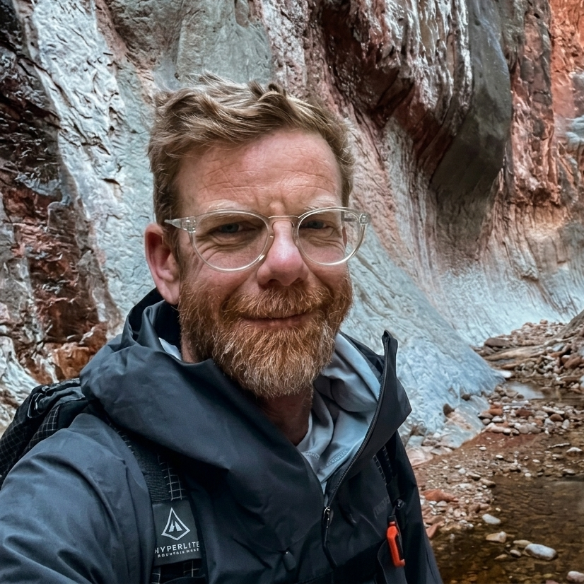A man wearing a hat and a jacket is taking a selfie in the snow.