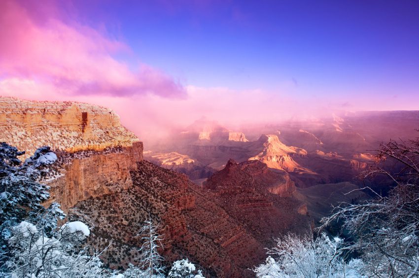 Snowy canyon cliffs at sunrise under a pink and purple sky