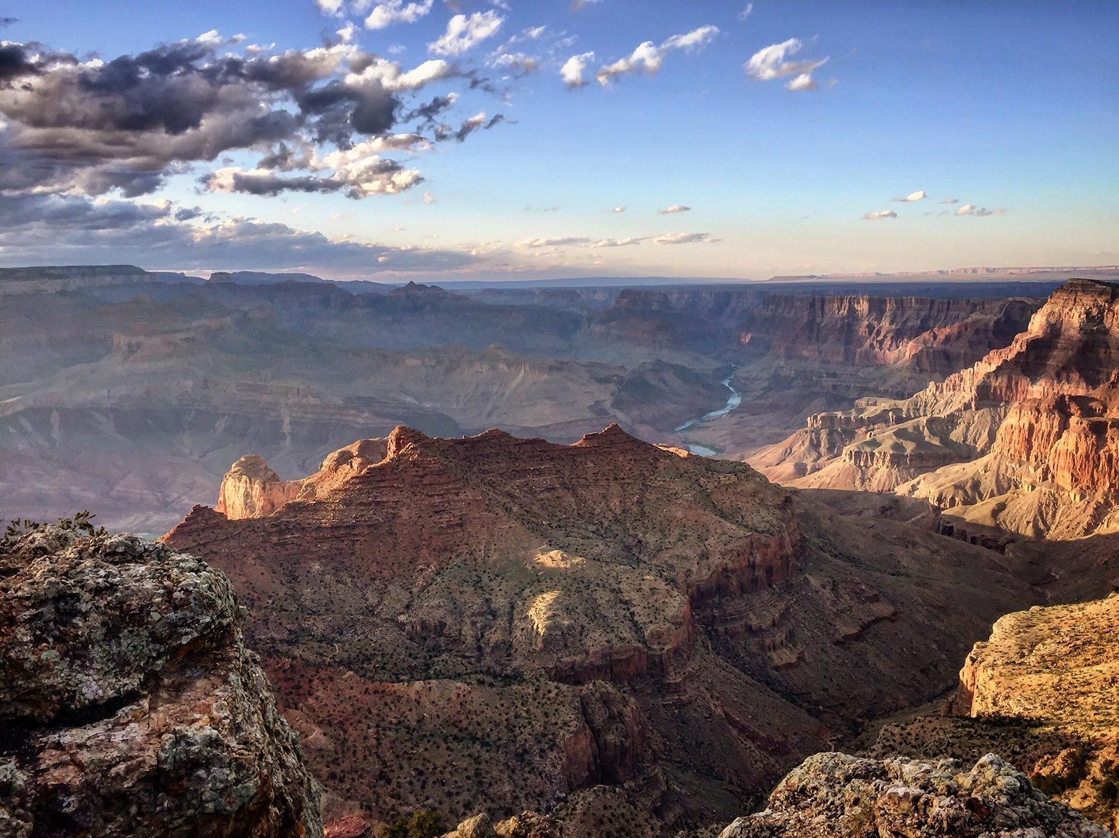 Sunlit canyon cliffs under a partly cloudy sky at sunset