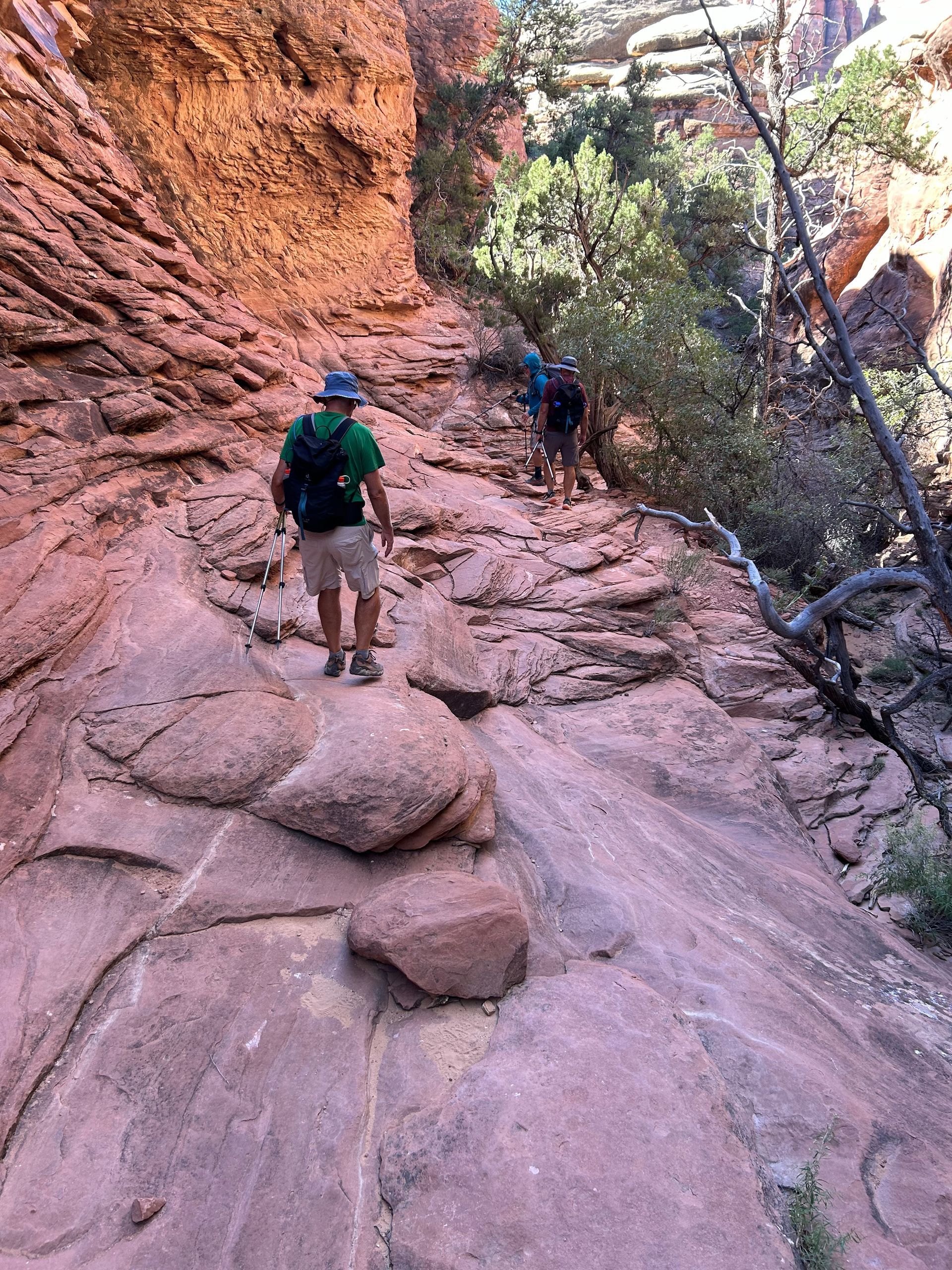 A man is walking down a rocky trail in the mountains.