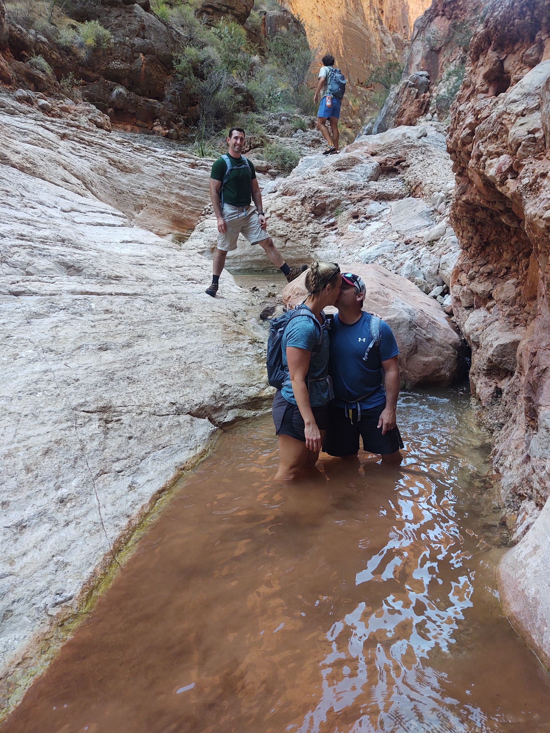 A man and a woman are standing in a river.