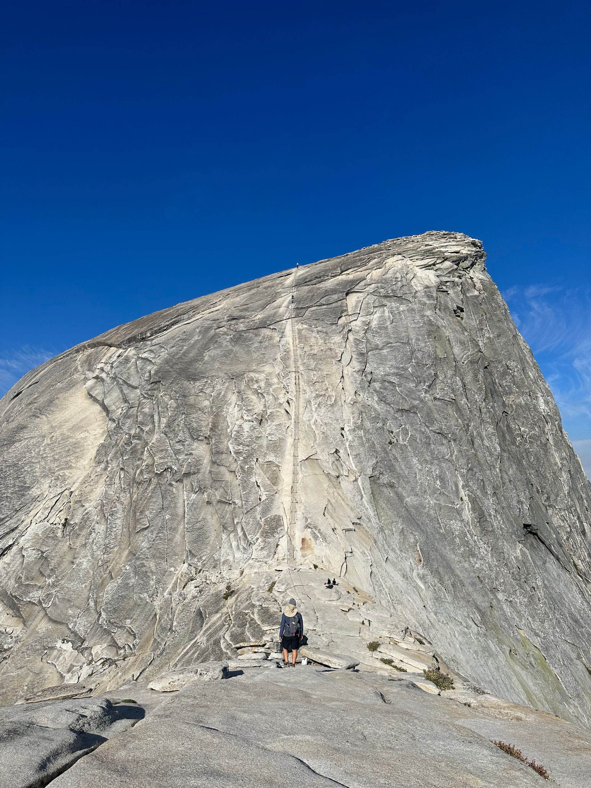 A person is standing on the edge of a large rocky mountain.