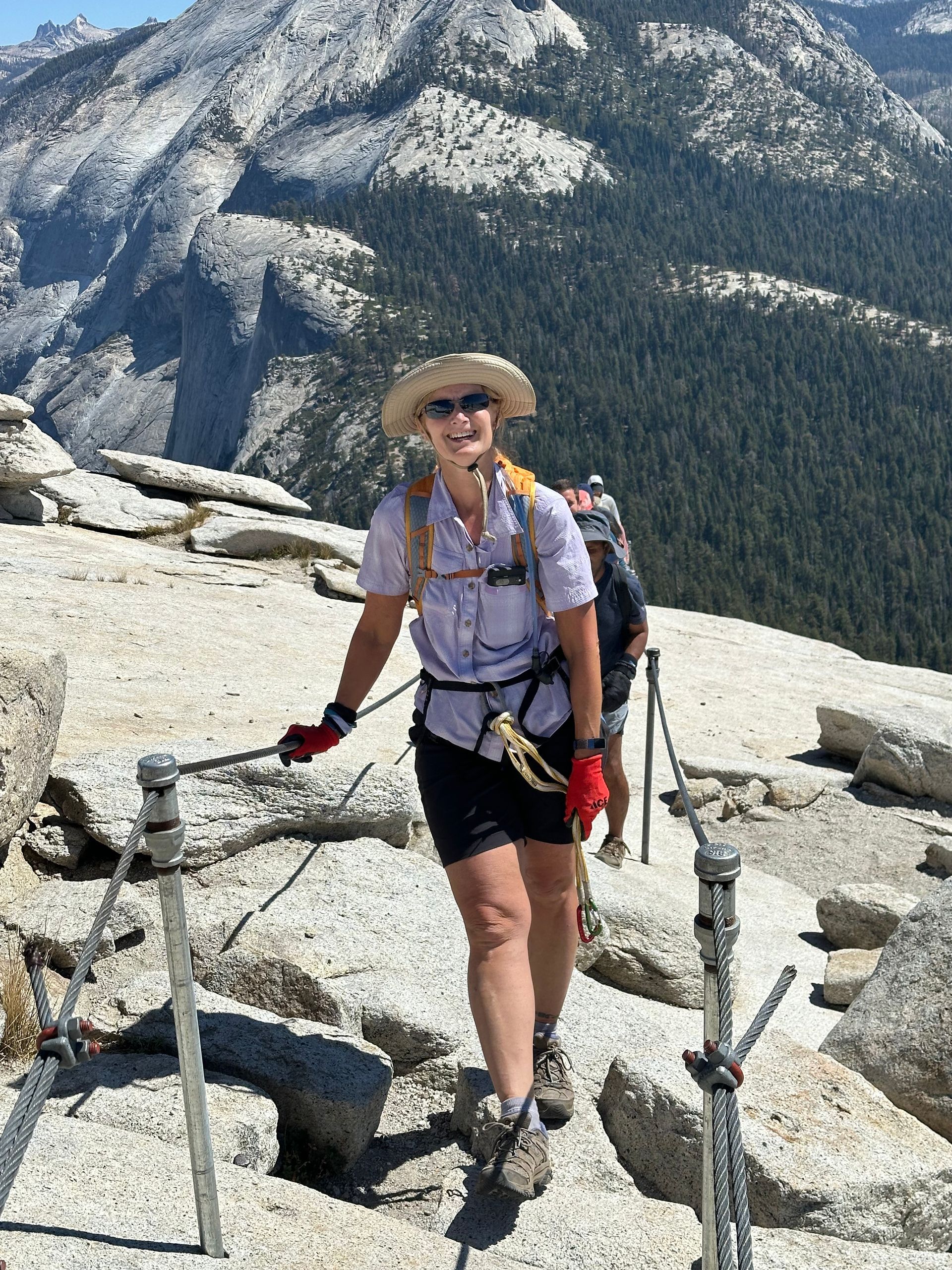 A woman is standing on top of a rocky mountain.