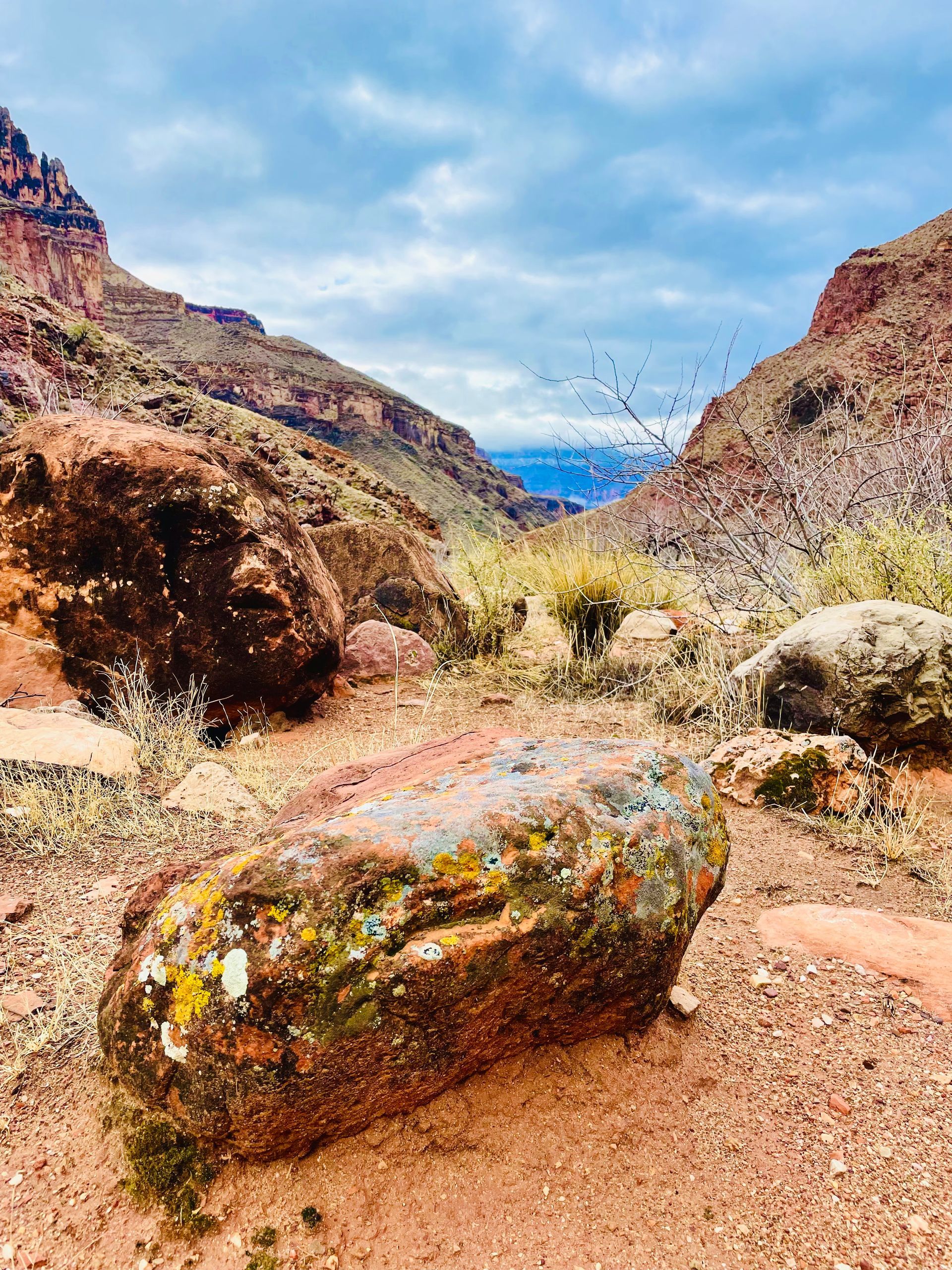 A large rock in the middle of a desert with mountains in the background.
