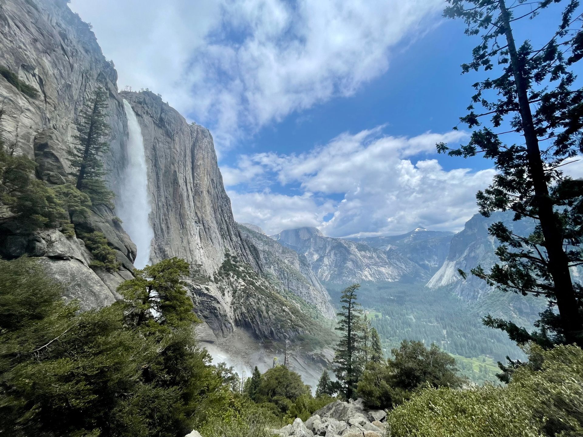 A waterfall in the middle of a mountain surrounded by trees.