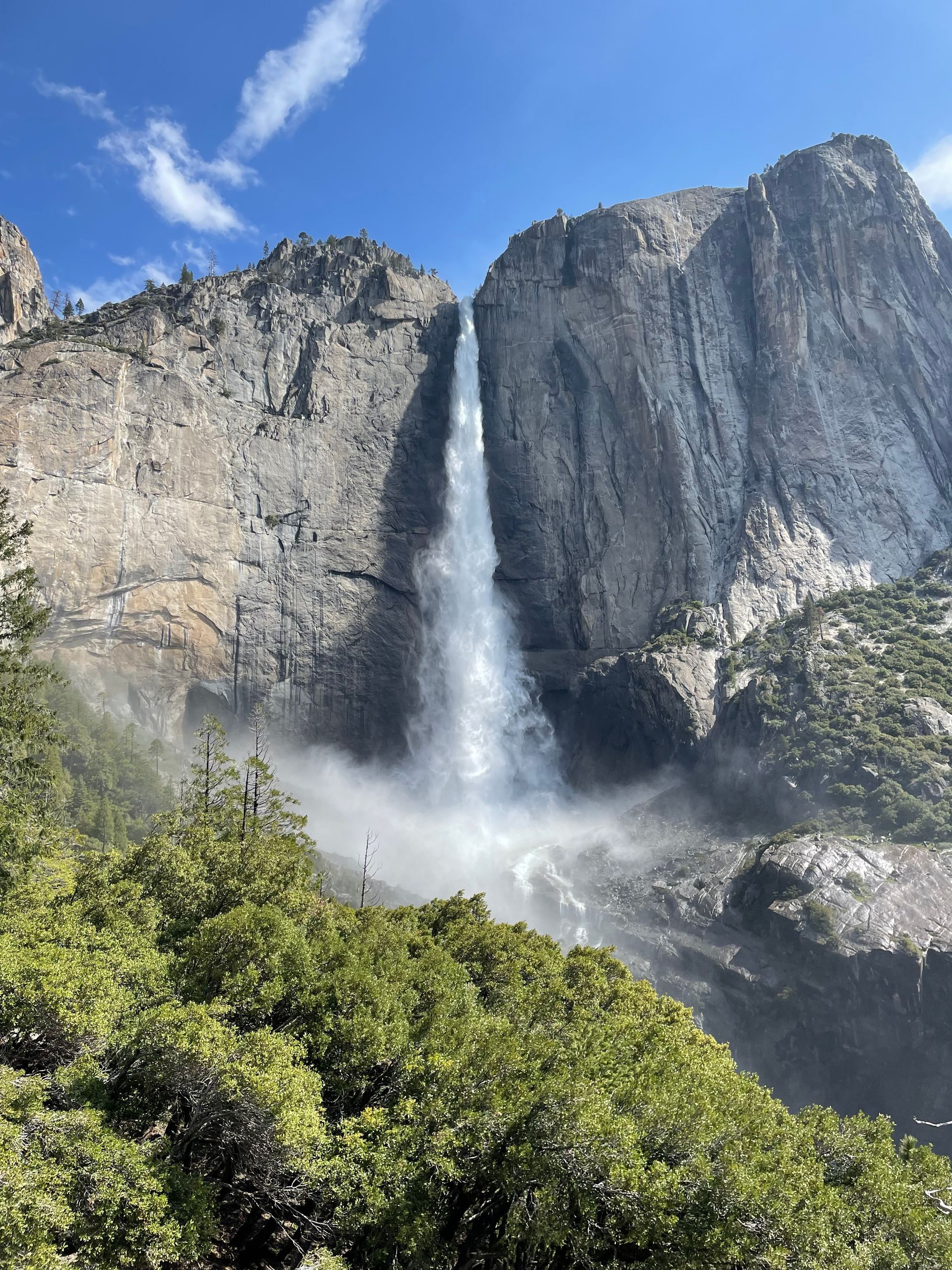 A waterfall in the middle of a mountain surrounded by trees.