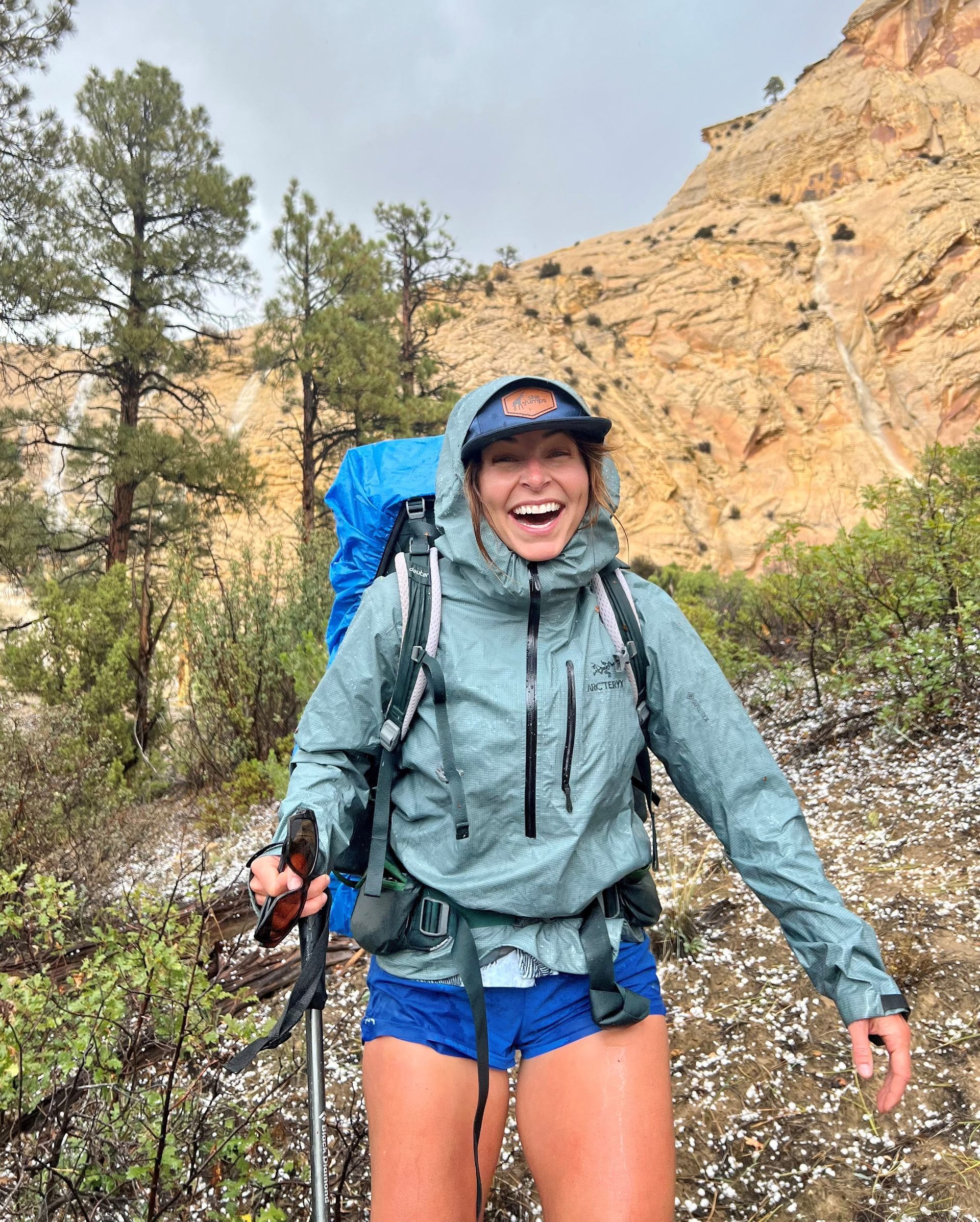 A woman is hiking in the mountains with a backpack and walking poles.