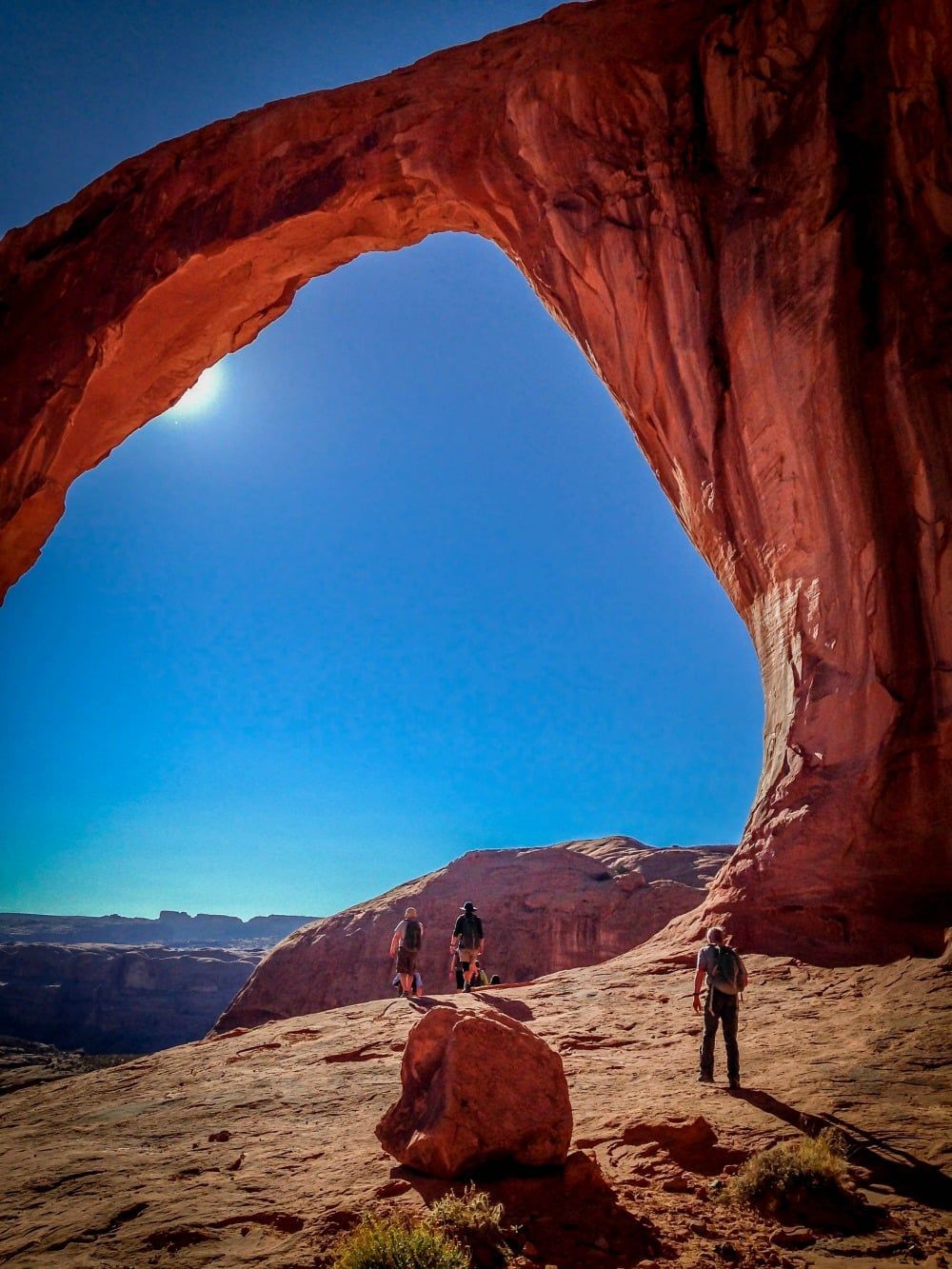 A group of people standing under an arch in the desert