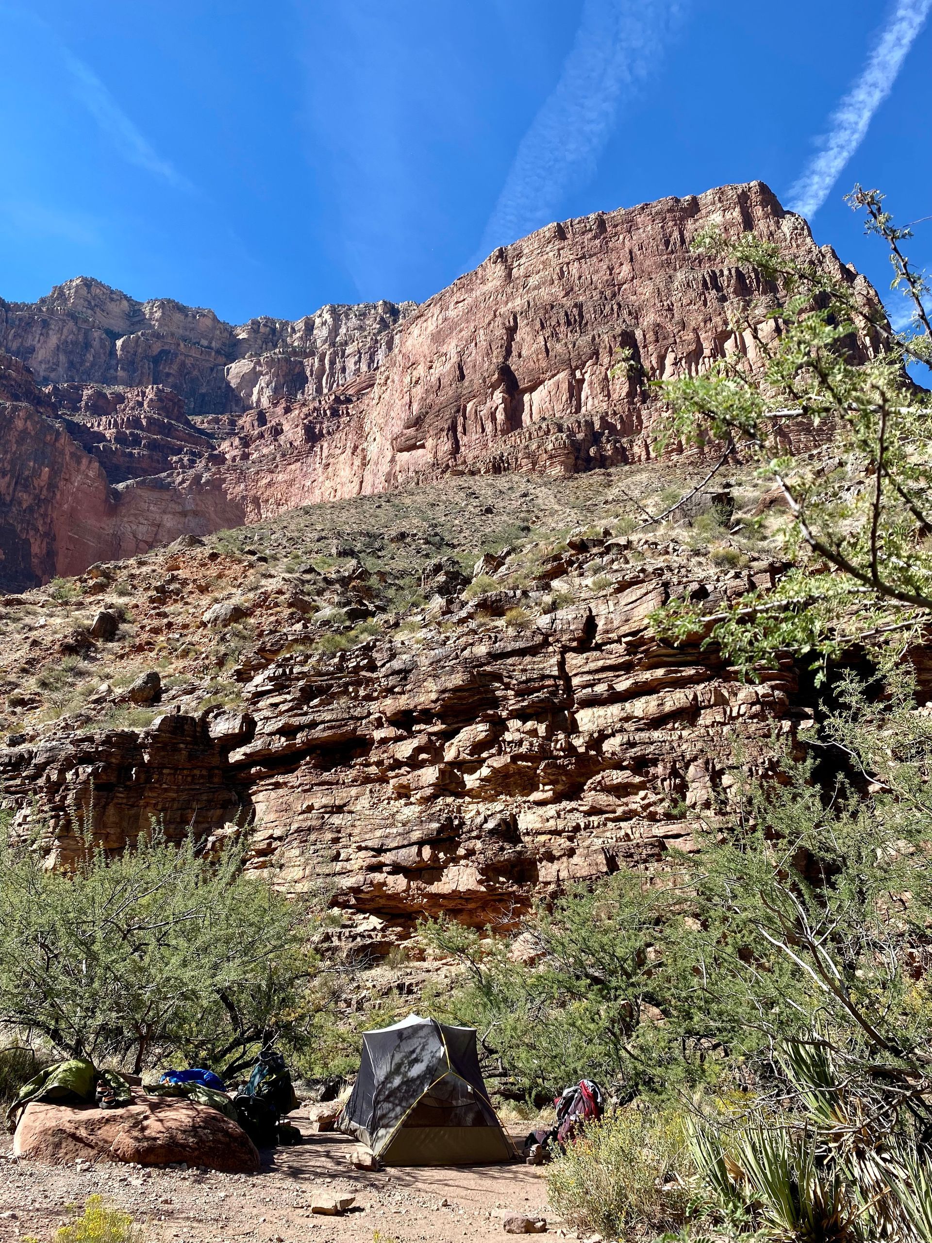A mountain covered in rocks and trees with a blue sky in the background