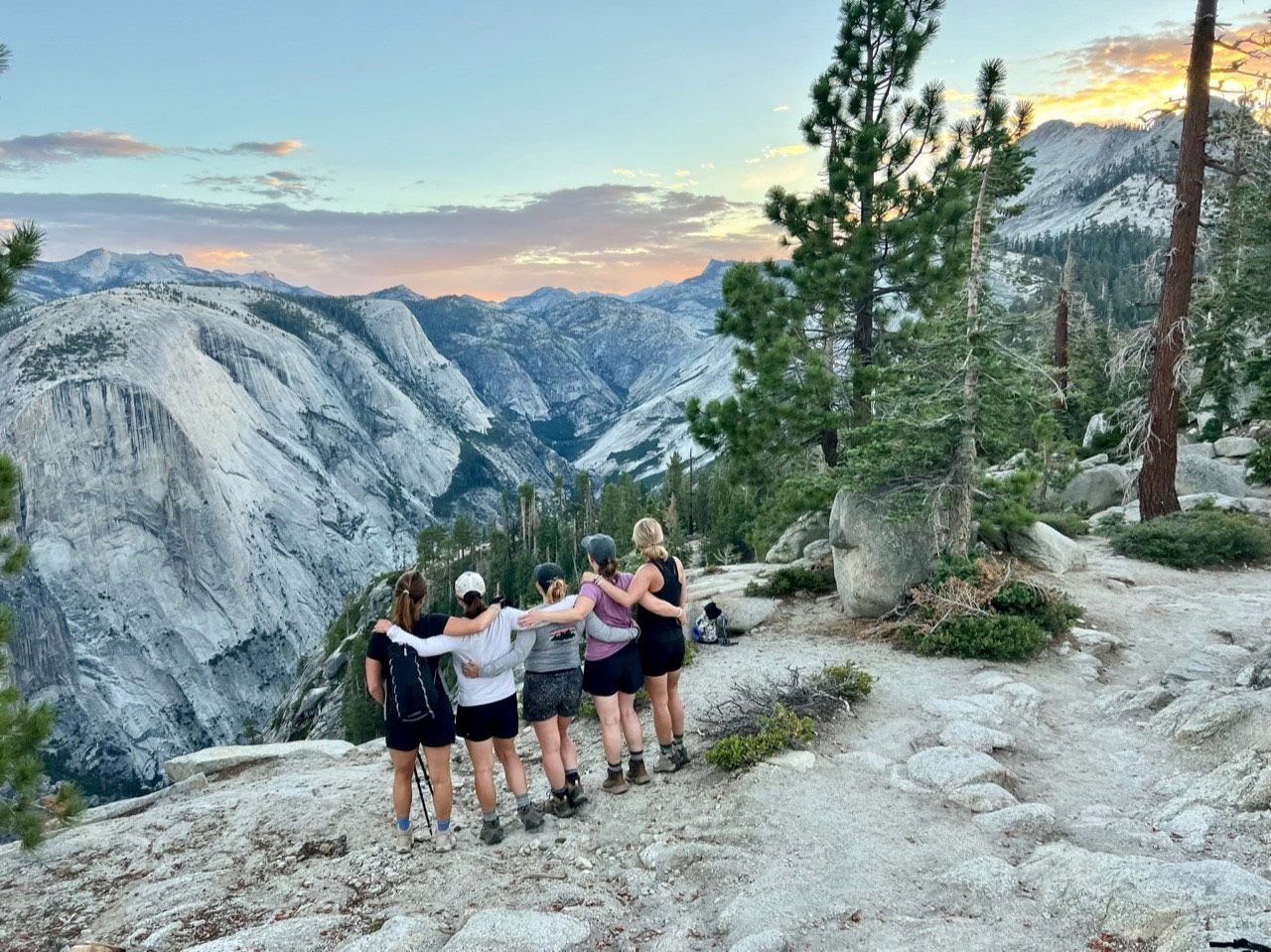A group of women are standing on top of a mountain.