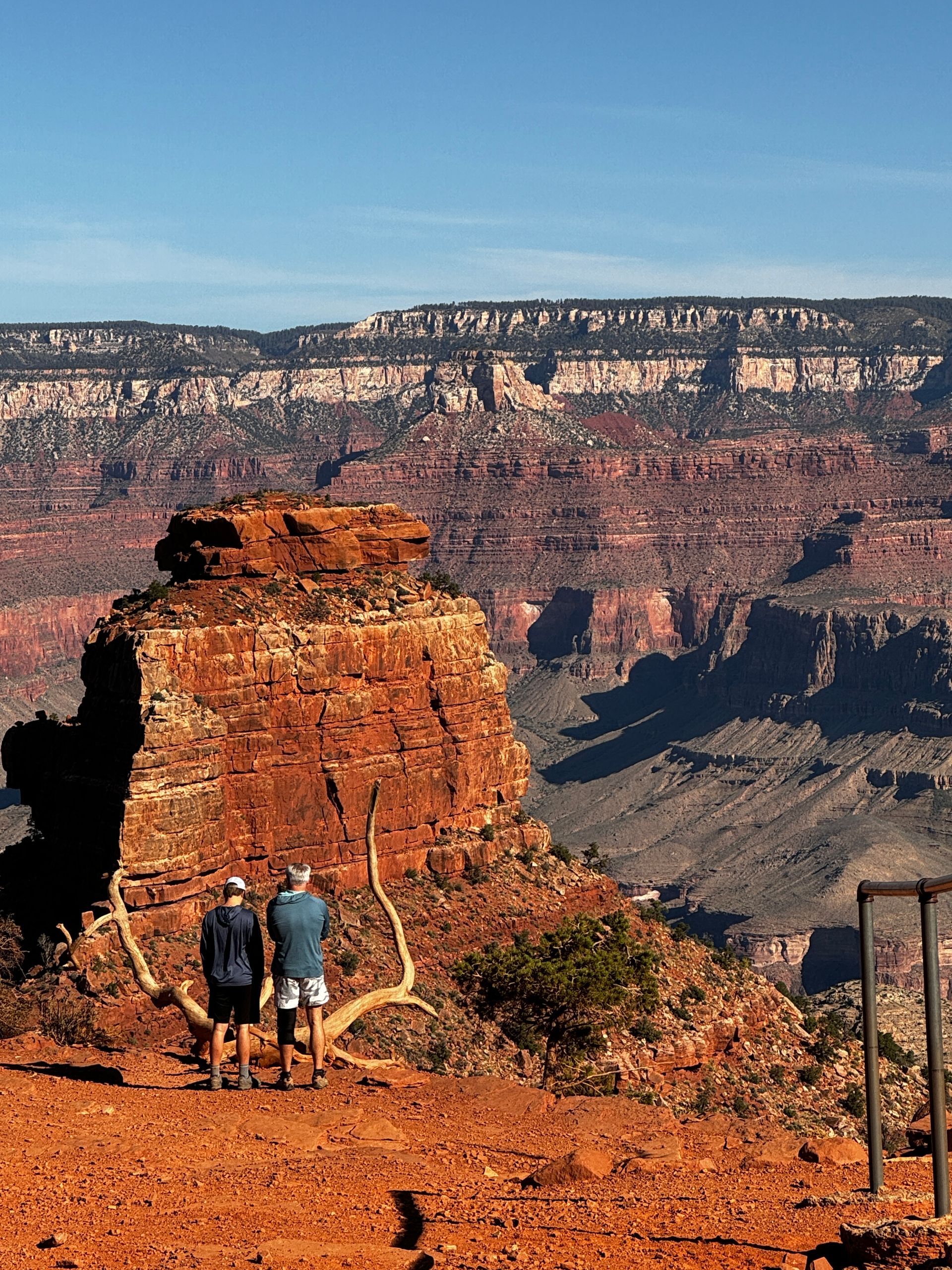 Two people standing on top of a rocky hill overlooking a canyon