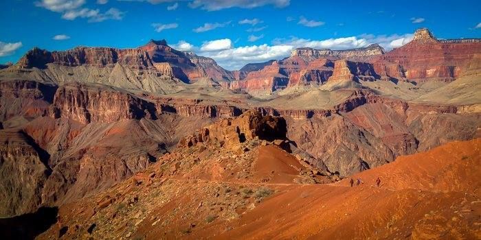 A group of people are walking on a trail in the grand canyon.