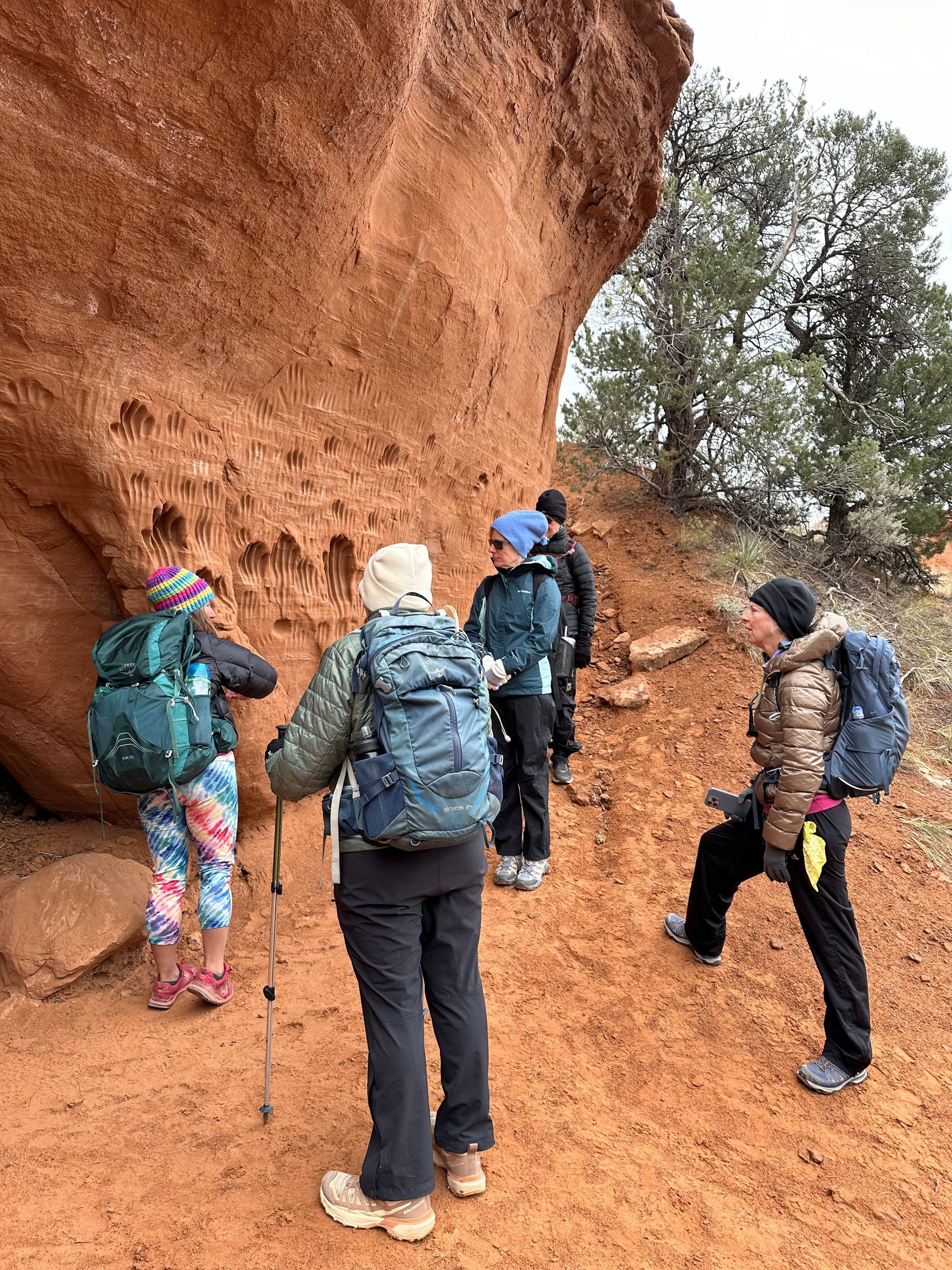 A group of people are standing next to a large rock.