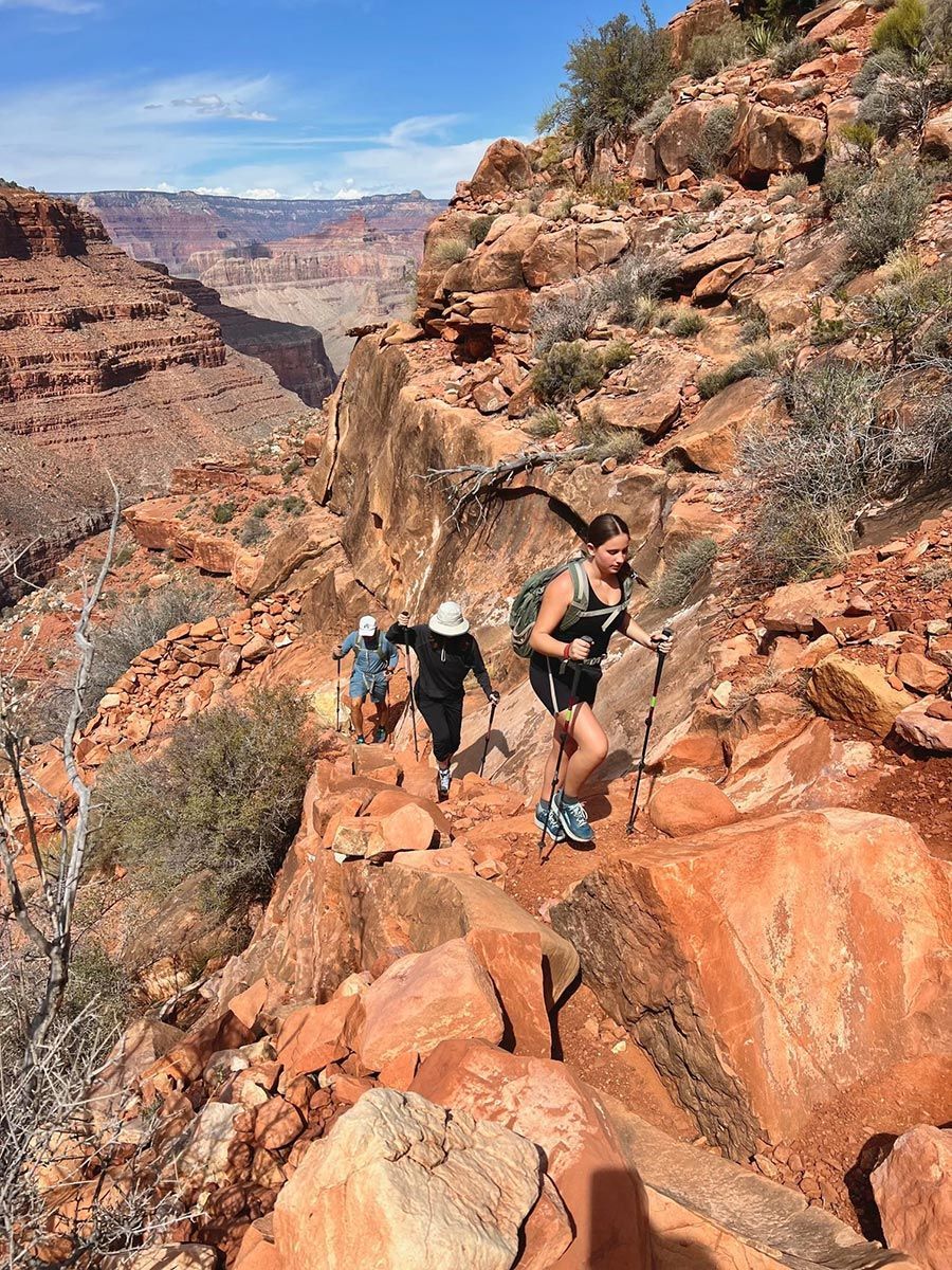 A group of people are hiking up a rocky trail in Grand Canyon.