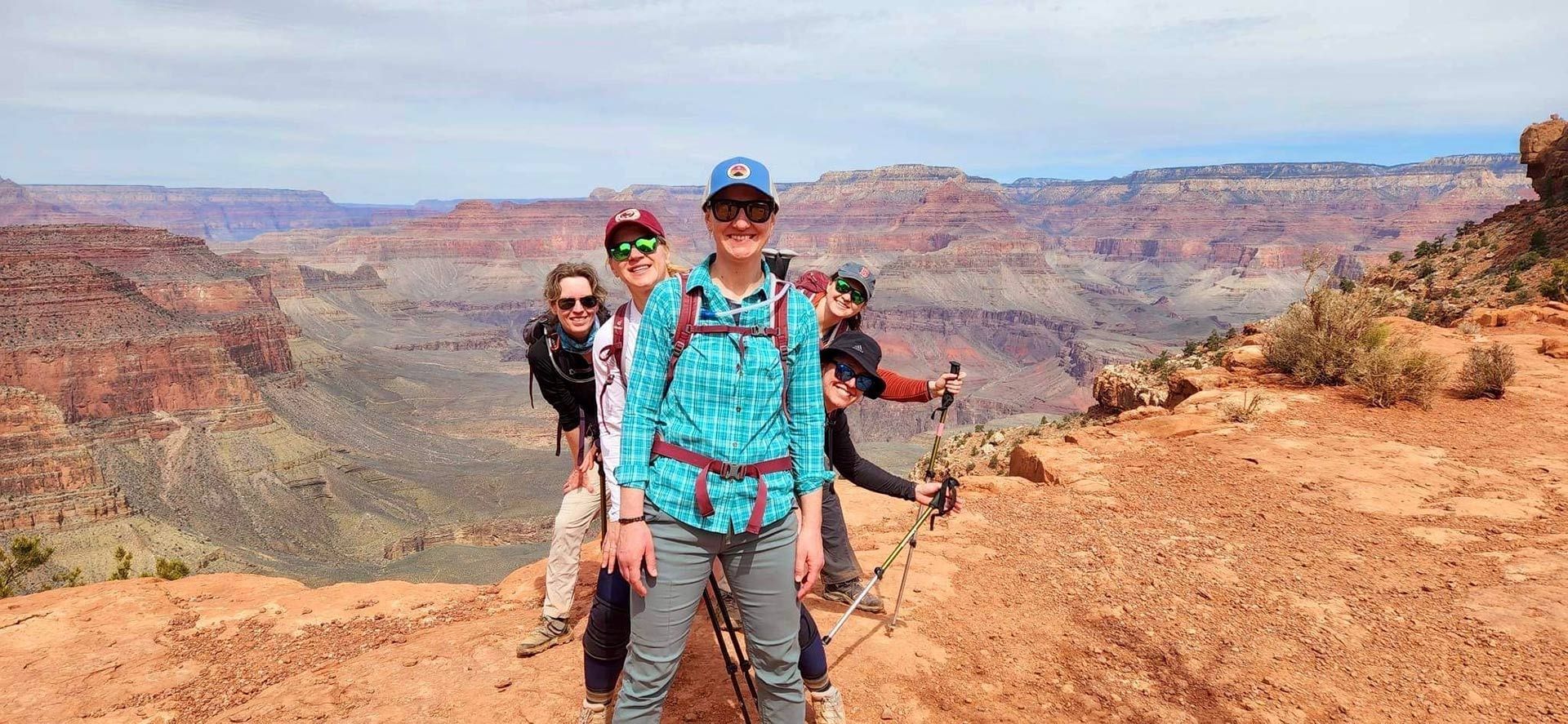Hikers posing on a rocky canyon overlook under a blue sky