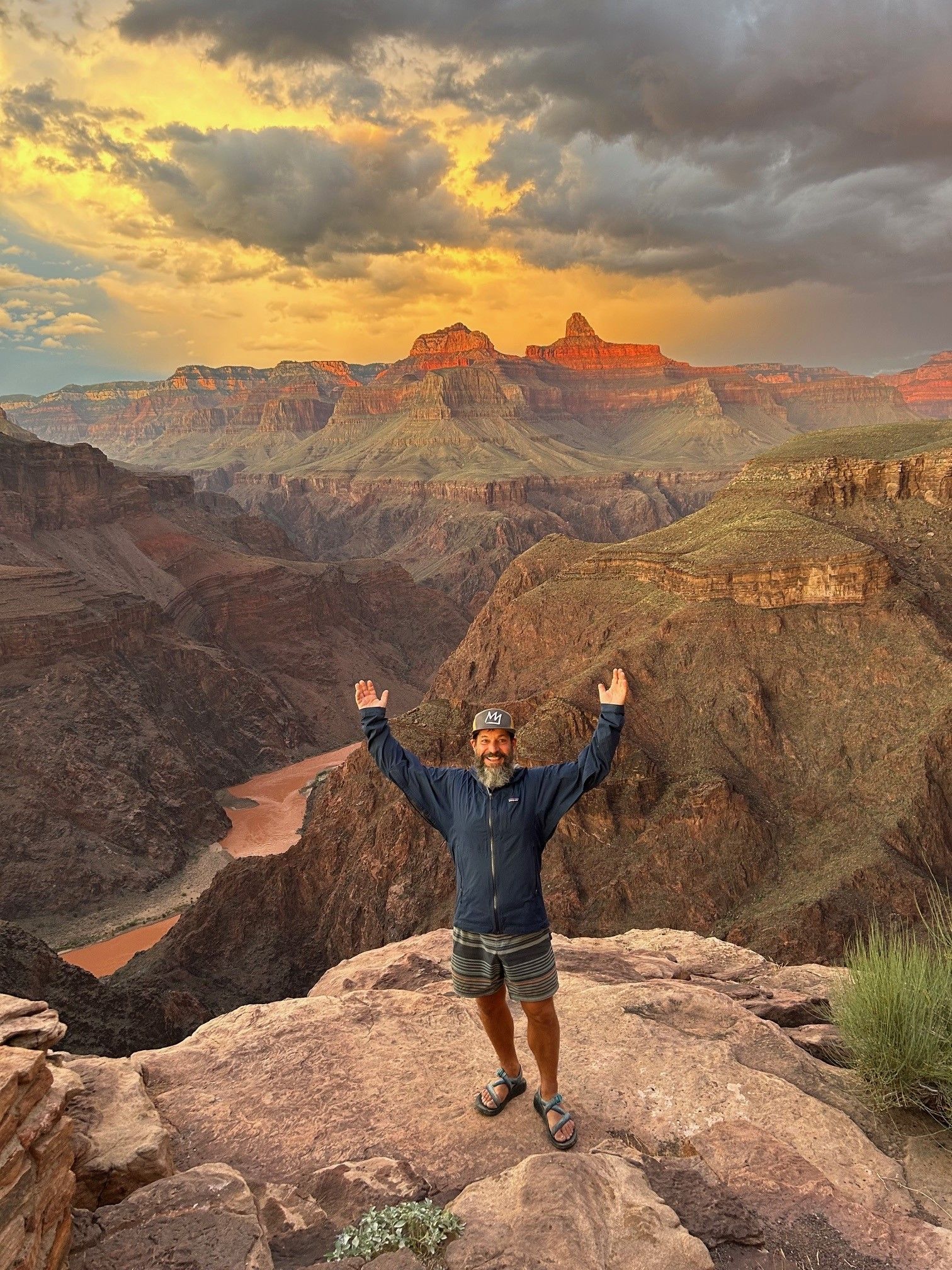A person holds their hands over their head next to a canyon