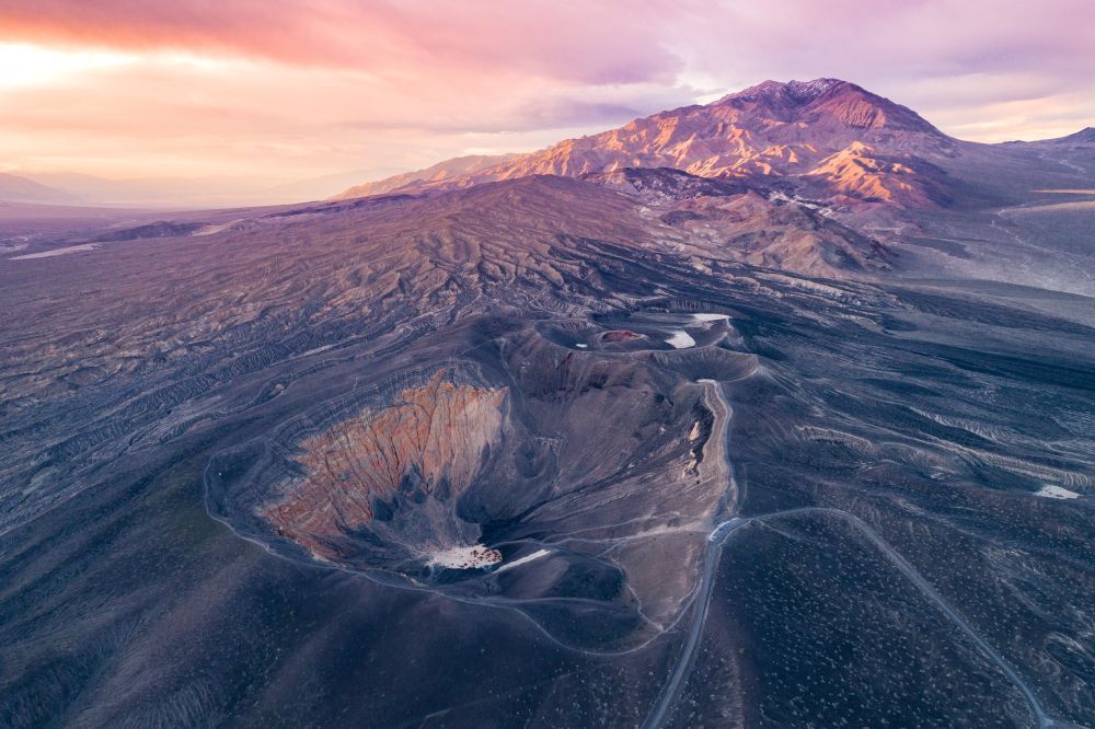 Aerial view of Ubehebe Crater in Death Valley at sunset, with light highlighting the rugged desert landscape.