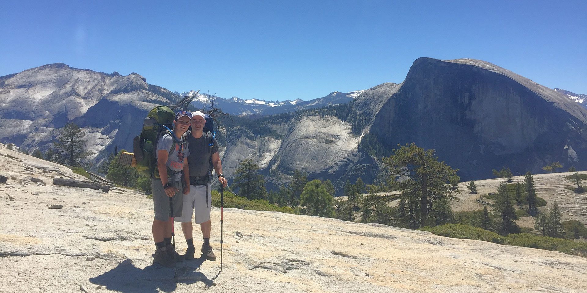 A couple of people standing next to each other on top of a mountain.