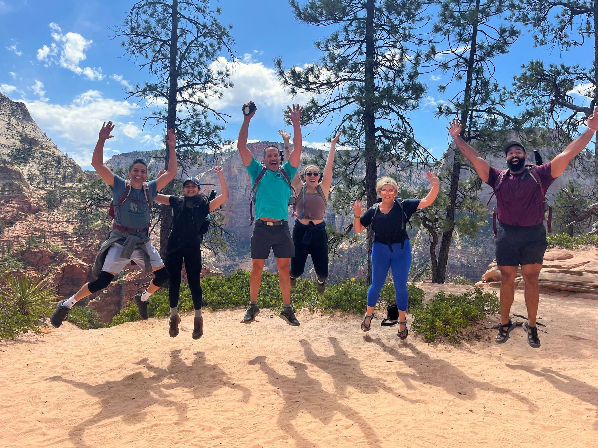 A group of people standing next to each other on top of a mountain.