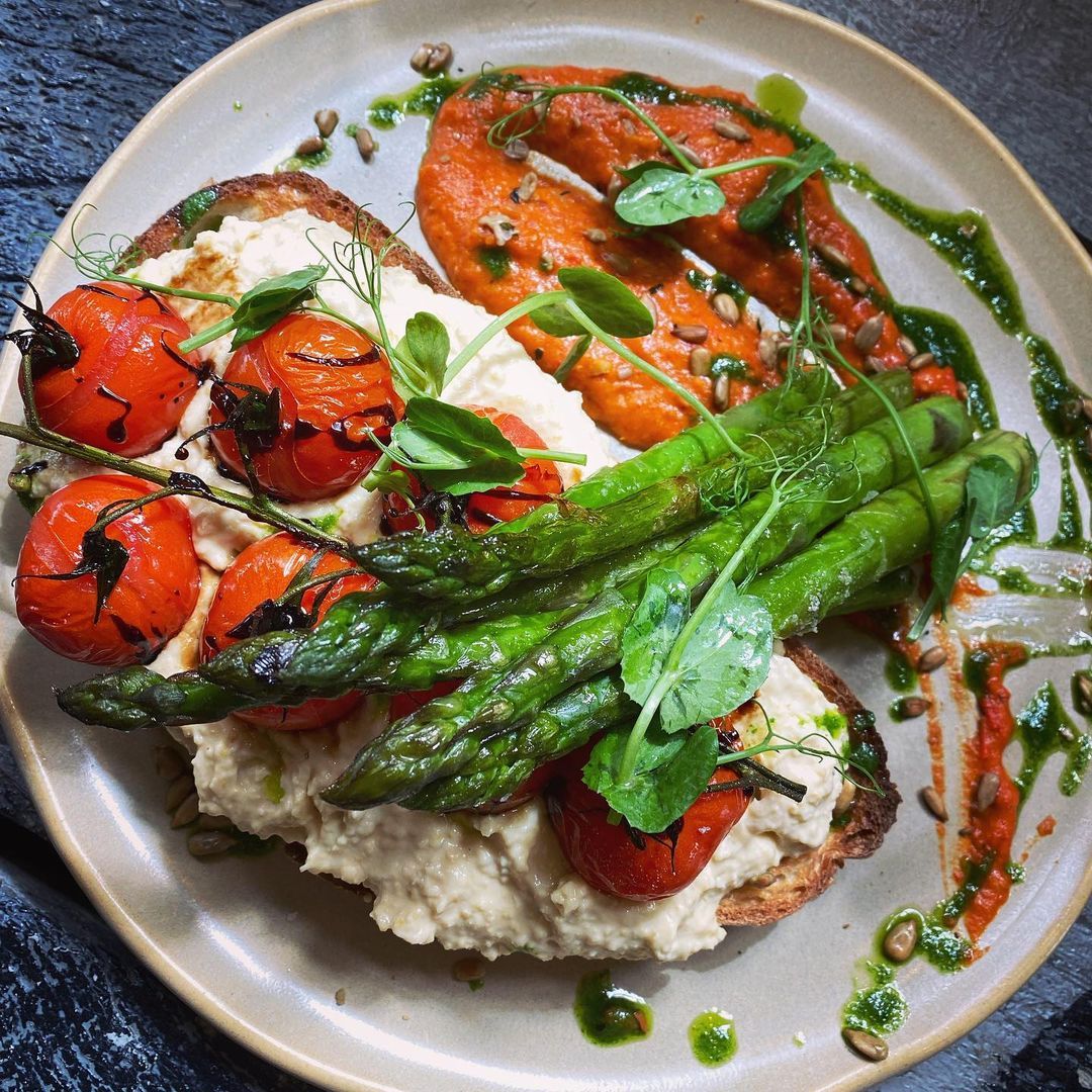 A plate of food with asparagus and tomatoes on toast.