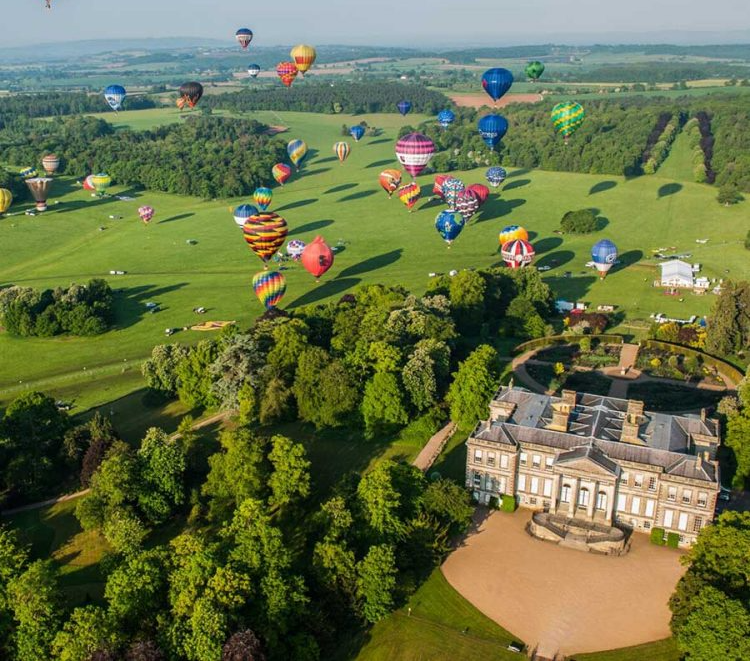 An aerial view of hot air balloons flying over a castle