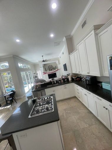 Bright modern kitchen with white cabinets, black countertops, and a central island under recessed lights.