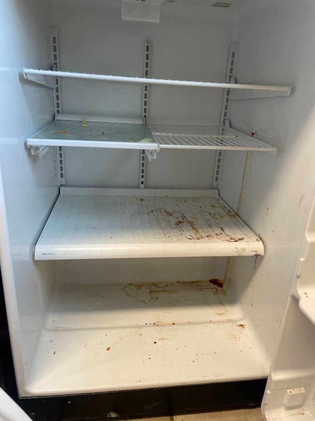 Empty white refrigerator shelves with food stains and residue inside.