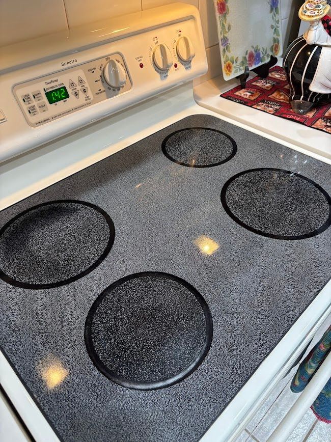 White electric stove with four black burners and speckled cooktop in a kitchen